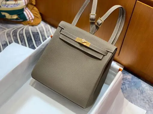 Hermes Kelly Ado Backpack Etoupe – Luxury Leather Backpack 2026 | Drip Kickz Hermès Kelly Ado Backpack Étoupe in Togo leather with gold hardware – a luxury backpack inspired by the iconic Hermès Kelly Bag.